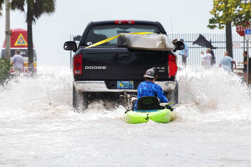 Un camión arrastra a un hombre en un kayak en un camino bajo después de una inundación tras el paso del huracán Ian, en Key West, Florida, el miércoles 28 de septiembre de 2022 por la tarde. (Foto AP/Mary Martin)