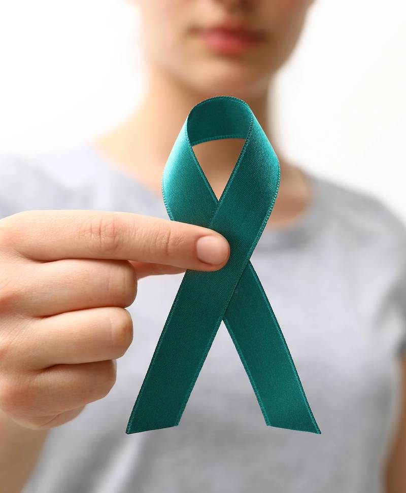 Una mujer sostiene un lazo color 'teal', o verde azulado, color que se utiliza como parte de la campaña de concientización sobre el cáncer cervical.