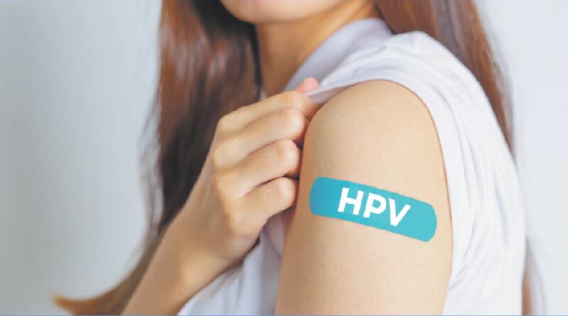 Una mujer muestra su brazo con una curita color "teal", o verde azulado, que lee "HPV" haciendo referencia a la vacuna contra el virus del papiloma humano.